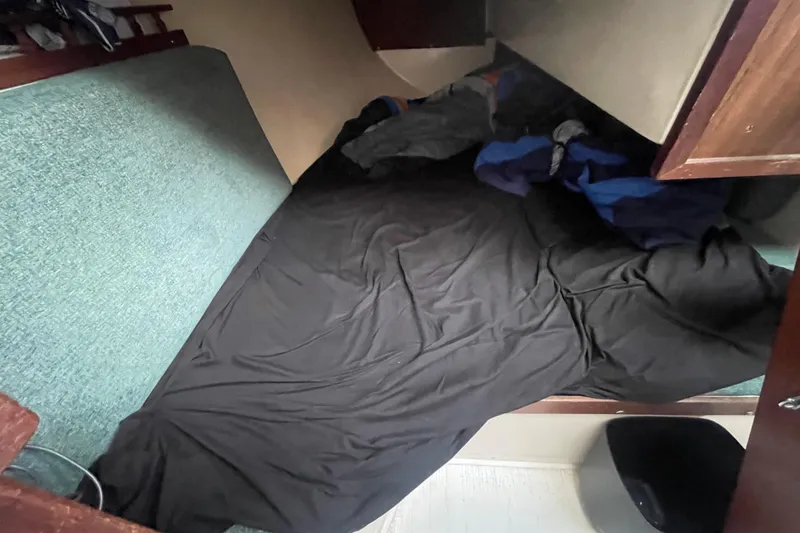 Slide: The Image of Cozy sleeping area inside a 1977 Catalina boat, featuring a black sheet and teal cushion. - 16
