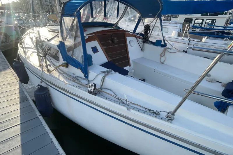 Slide: The Image of 1977 Catalina sailboat docked, featuring blue canopy and white deck, in marina setting. - 3