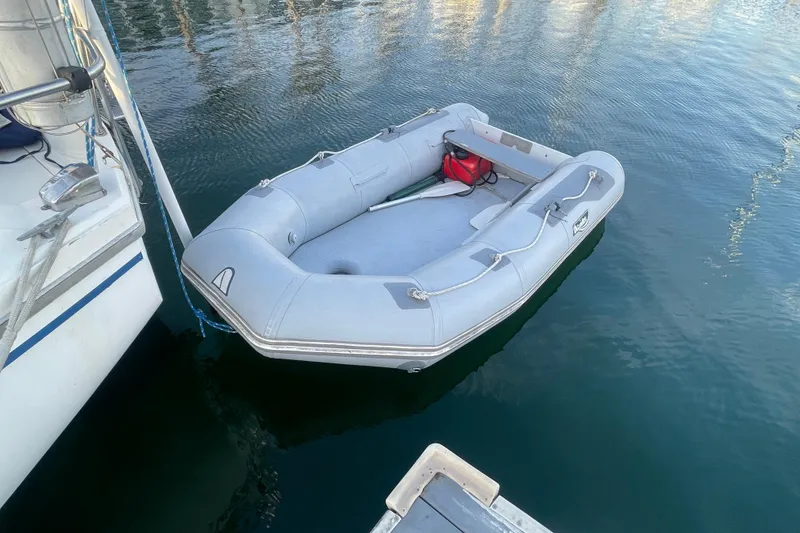 Slide: The Image of Inflatable dinghy moored beside a 1977 Catalina boat on calm water. - 7