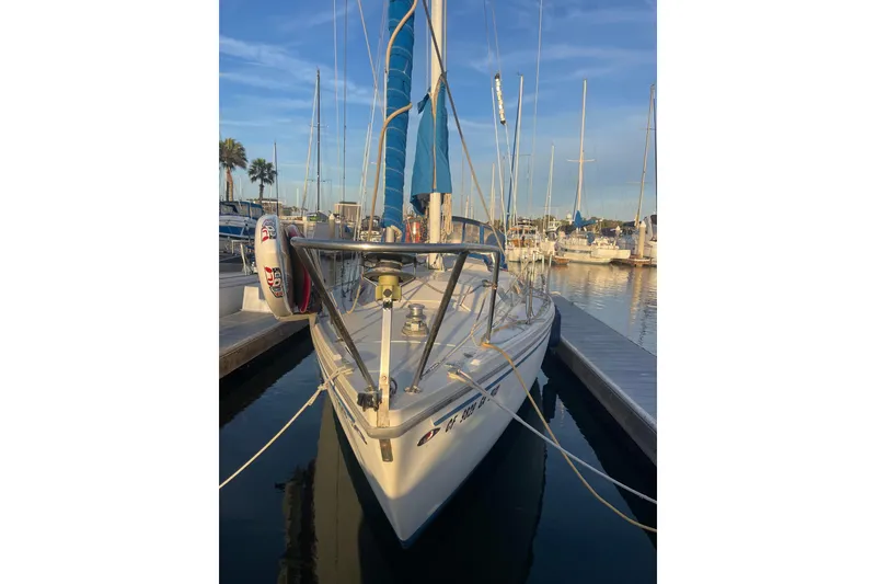 Slide: The Image of 1977 Catalina sailboat docked at marina, featuring blue sails and calm waters. - 8