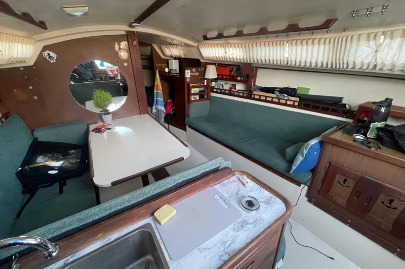 Slide: The Image of Interior of a 1977 Catalina boat with cozy seating and a dining area. - 9
