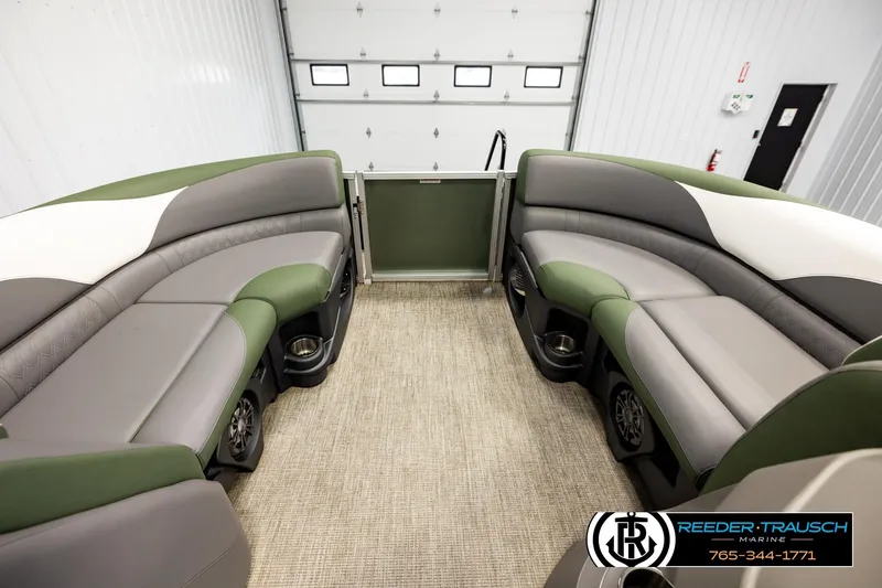Slide: The Image of 2024 Avalon LSZ CRB pontoon boat interior with green and gray seating in a showroom. - 18