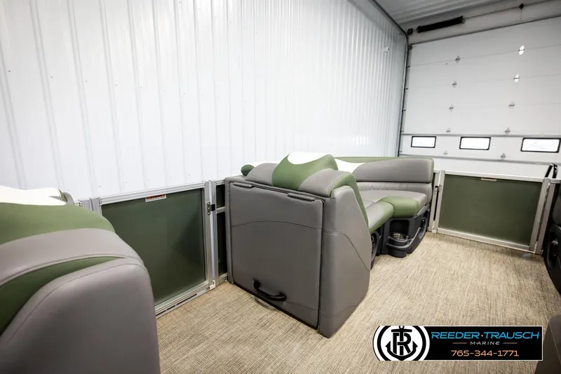 Slide: The Image of 2024 Avalon LSZ CRB pontoon boat interior with green and gray seating in a showroom. - 26