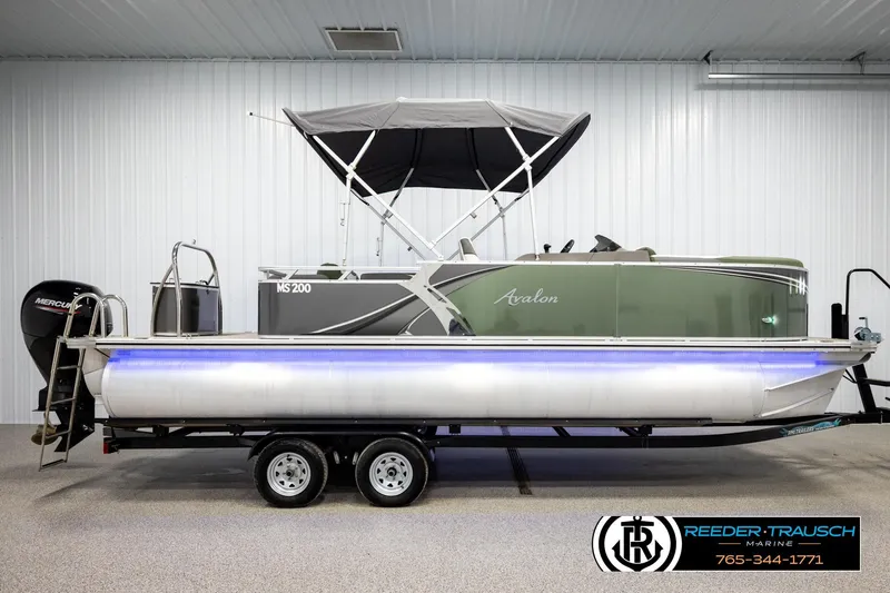 Slide: The Image of 2024 Avalon LSZ CRB pontoon boat with canopy, displayed indoors on a trailer. - 5