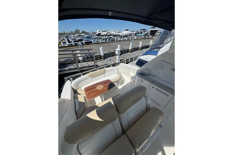 Slide: The Image of 2010 Searay 330 Sundancer boat interior with cushioned seating and wooden table. - 20