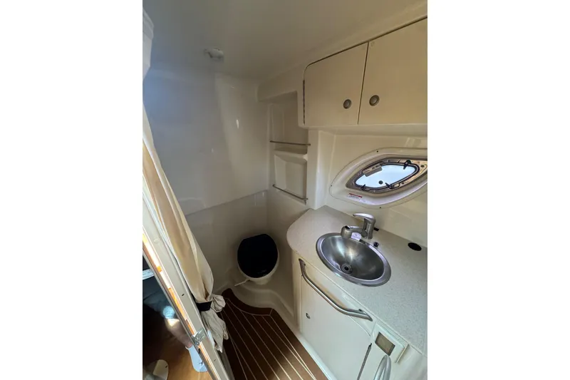 Slide: The Image of 2010 Searay 330 Sundancer interior with kitchenette, featuring wood cabinetry and compact design. - 24