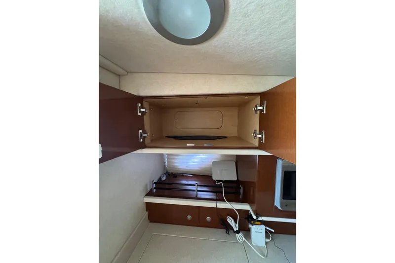 Slide: The Image of 2010 Searay 330 Sundancer yacht kitchenette with microwave, sink, and storage cabinets. - 27