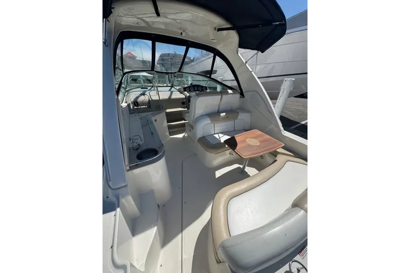 Slide: The Image of 2010 Searay 330 Sundancer cockpit with seating, table, and helm under a canopy. - 7