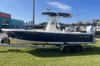 Slide: The Image of 2022 Sea Born LX24 Center Console boat on a trailer, parked on grass. - 5