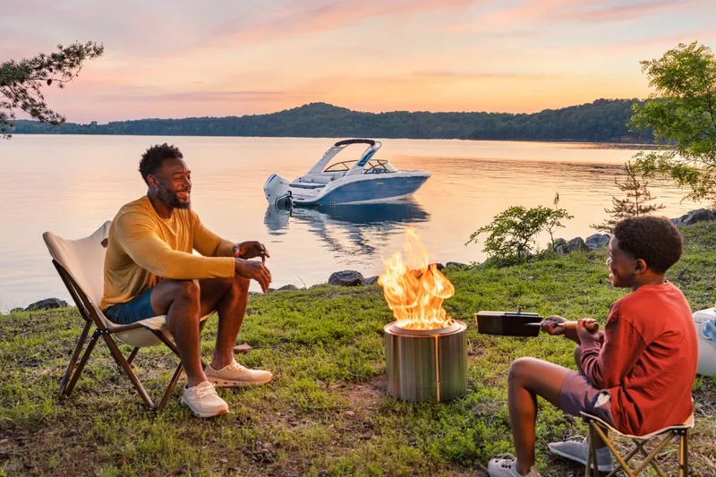 Slide: The Image of Father and son by campfire with Sea Ray SDX 230 boat in background. - 20