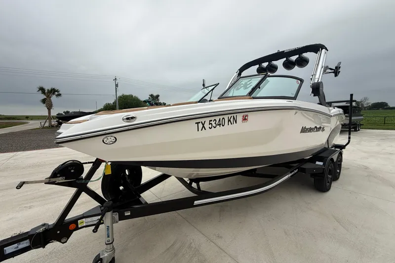 Slide: The Image of 2022 MasterCraft NXT22 boat on trailer, parked outdoors with overcast sky. - 3