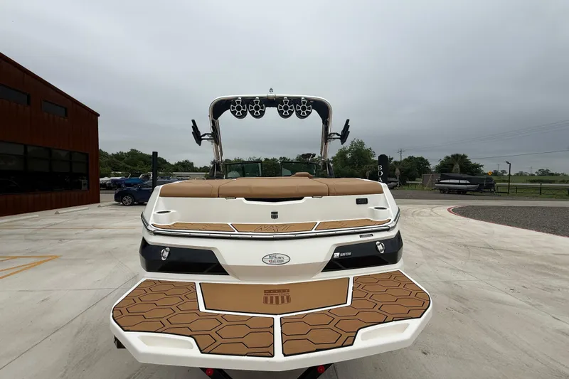 Slide: The Image of 2022 MasterCraft NXT22 boat with tan seating and wakeboard tower, parked outdoors. - 6