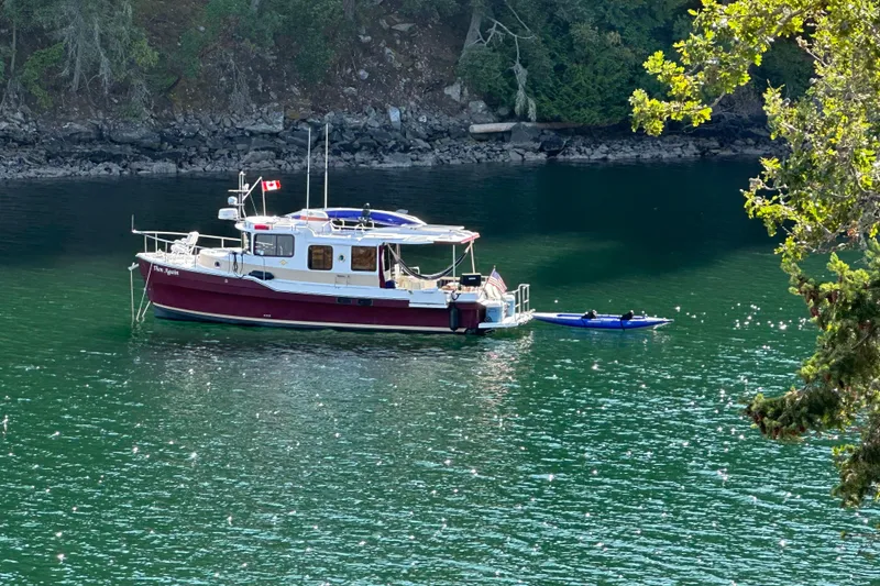 The Image of 2018 Ranger Tugs R-31 S boat anchored in a serene, forested cove. - 0