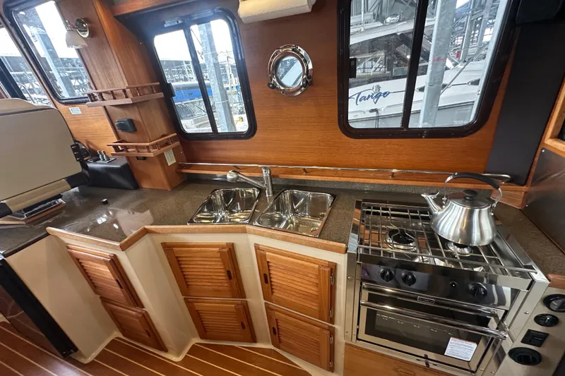 Slide: The Image of 2018 Ranger Tugs R-31 S interior kitchen with stove, sink, and wooden cabinetry. - 13