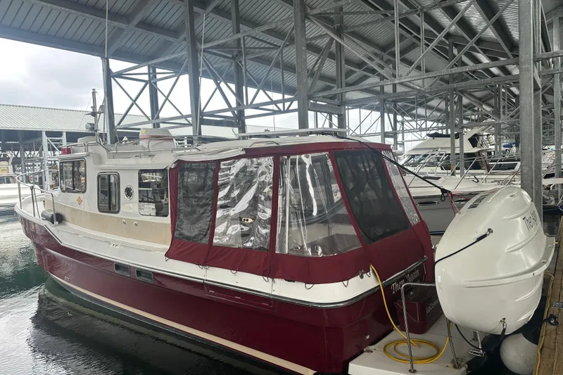 Slide: The Image of 2018 Ranger Tugs R-31 S docked in a covered marina, featuring a red and white exterior. - 18