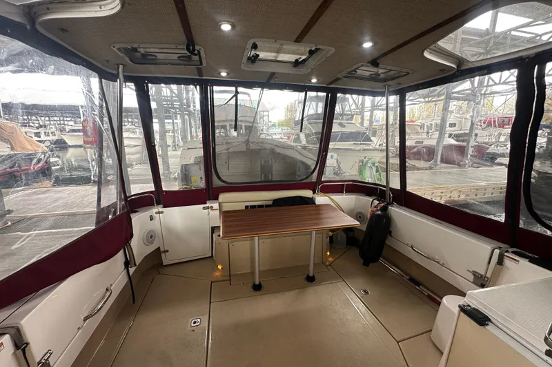 Slide: The Image of 2018 Ranger Tugs R-31 S cockpit with table, enclosed by clear panels at marina. - 22