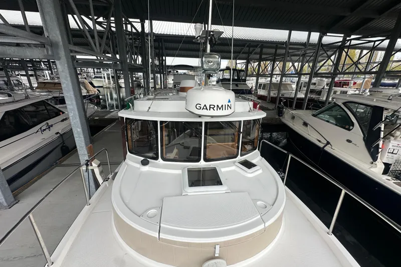 Slide: The Image of 2018 Ranger Tugs R-31 S boat docked in a covered marina, featuring Garmin equipment. - 50