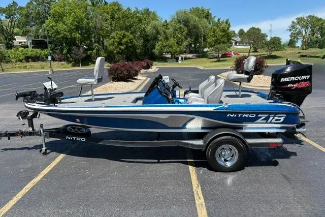 Slide: The Image of 2018 Nitro Z18 boat with trailer, parked outdoors, featuring a sleek blue and silver design. - 13