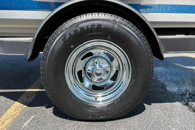 Slide: The Image of Chrome wheel of a 2018 Nitro Z18 boat trailer on asphalt pavement. - 18