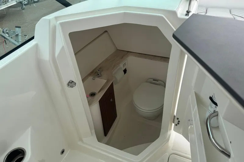 Slide: The Image of Interior view of 2022 Pursuit DC 266 Dual Console boat's compact bathroom. - 12