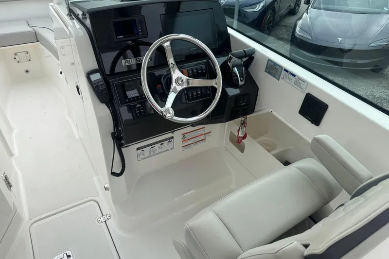 Slide: The Image of 2022 Pursuit DC 266 Dual Console boat interior with steering wheel and control panel. - 13