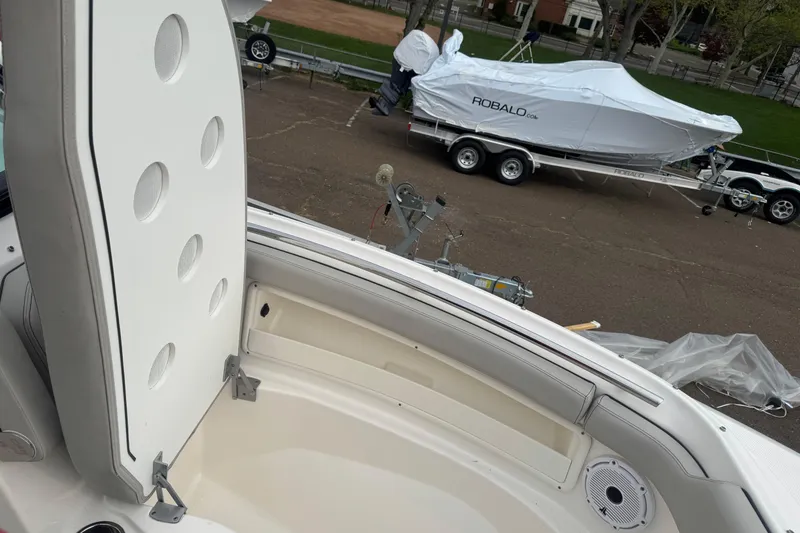 Slide: The Image of 2022 Pursuit DC 266 Dual Console boat interior with seating and storage, parked near covered Robalo boat. - 18