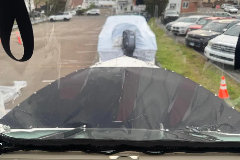 Slide: The Image of 2022 Pursuit DC 266 Dual Console boat parked, covered, in a lot with surrounding vehicles. - 22