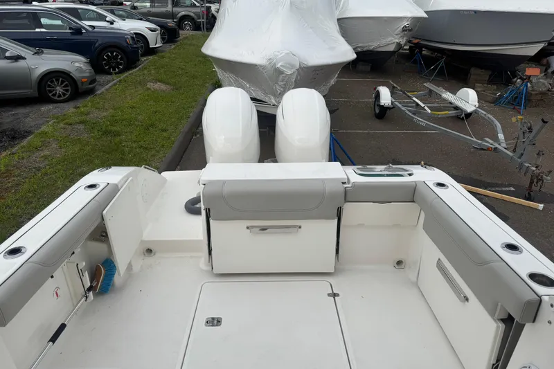 Slide: The Image of 2022 Pursuit DC 266 Dual Console boat interior with seating and storage, parked near other boats. - 5