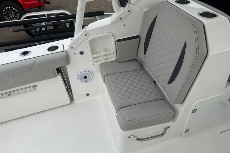 Slide: The Image of 2022 Pursuit DC 266 Dual Console boat interior with gray cushioned seating and cup holders. - 7