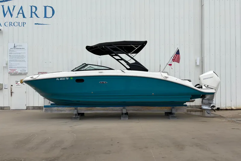 The Image of 2024 Sea Ray SDX 270 Outboard boat with teal hull and black canopy, docked indoors. - 0
