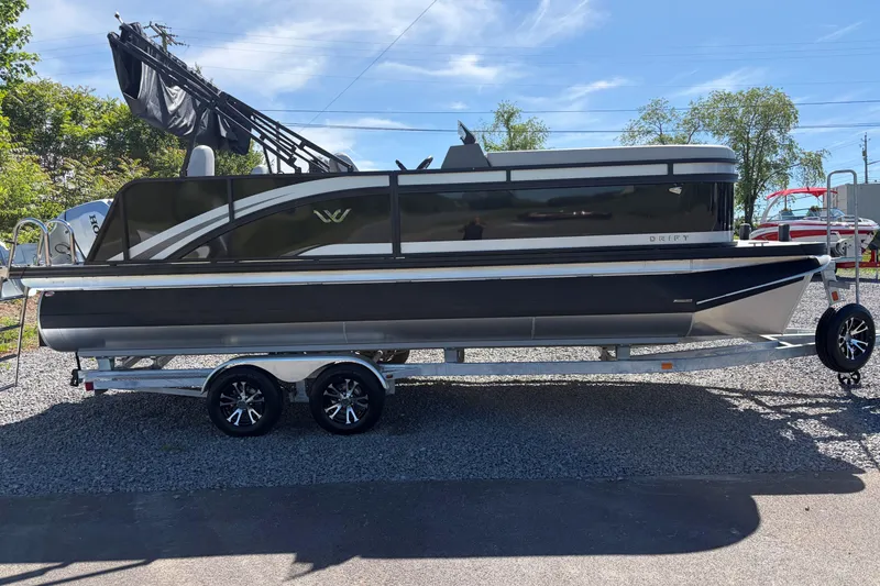 The Image of 2026 Whisper D21 XRE CRUISE pontoon boat on trailer, parked outdoors. - 0