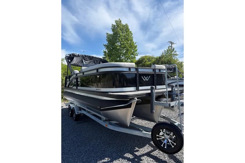 Slide: The Image of 2026 Whisper D21 XRE CRUISE pontoon boat on trailer, parked outdoors. - 2