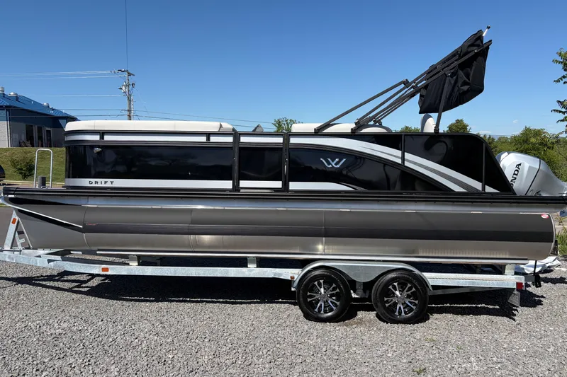 Slide: The Image of 2026 Whisper D21 XRE CRUISE pontoon boat on trailer, sleek black design under clear sky. - 4