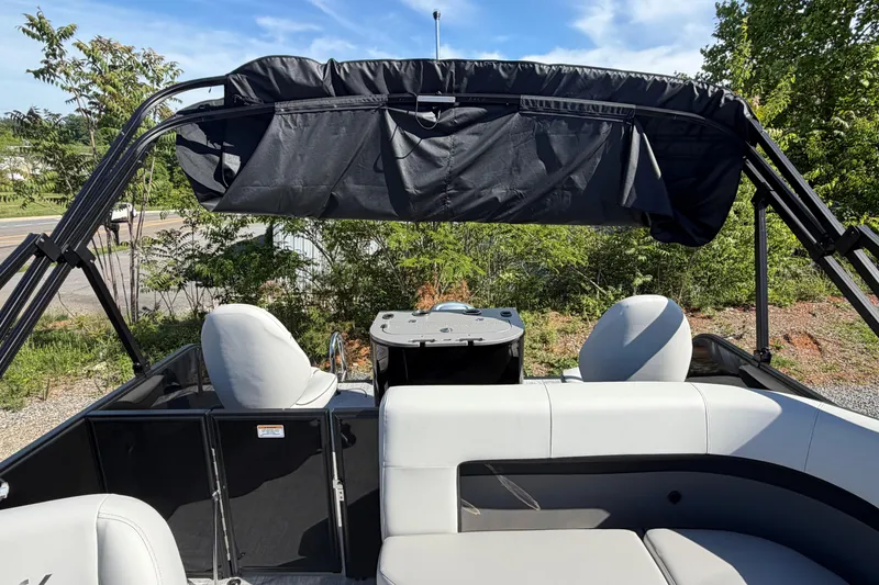 Slide: The Image of 2026 Whisper D21 XRE CRUISE boat interior with canopy and seating, surrounded by greenery. - 8