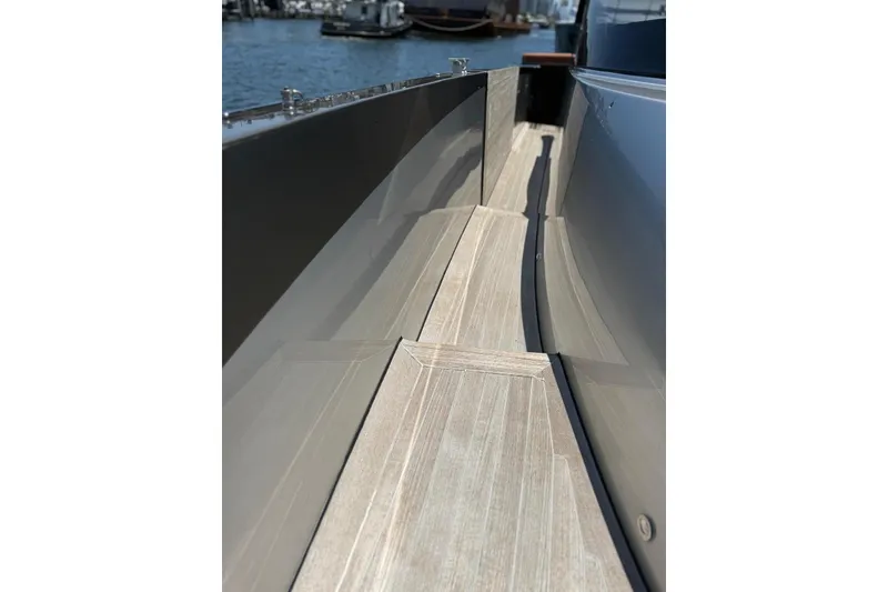 Slide: The Image of 2015 CNM Continental yacht deck with sleek wooden finish, docked by the water. - 18