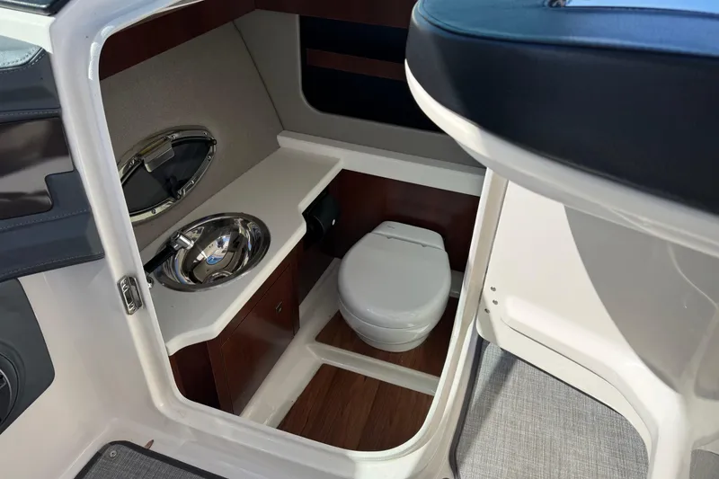 Slide: The Image of 2021 Chaparral 307 SSX boat interior with compact bathroom, featuring a toilet and sink. - 4
