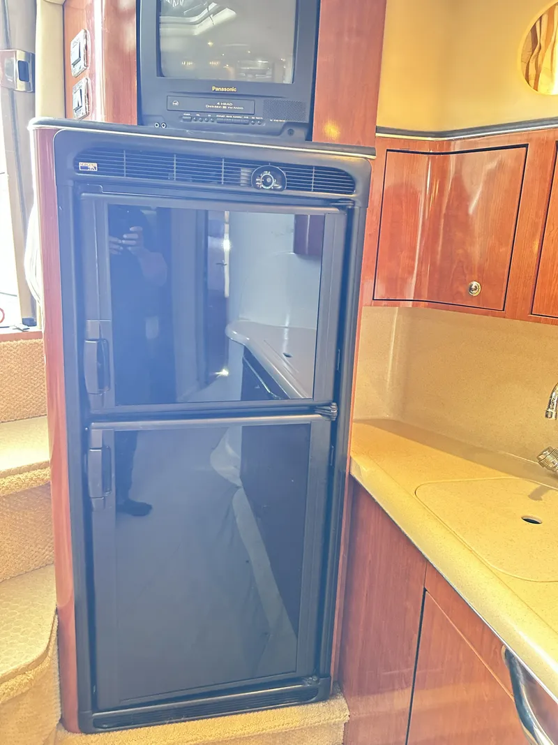 Slide: The Image of Sea Ray 410 Express Cruiser 2003 kitchen area with fridge and TV. - 45