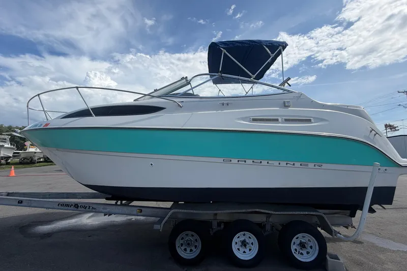 Slide: The Image of 2004 Bayliner 2452 Ciera Express boat on trailer under a partly cloudy sky. - 9