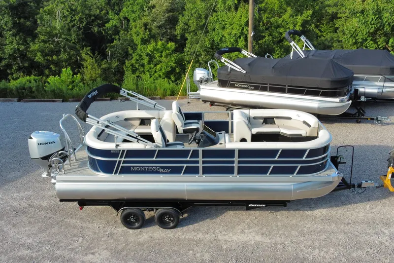 The Image of 2026 Montego Bay 8522 BR DLX pontoon boat on trailer, surrounded by greenery. - 1