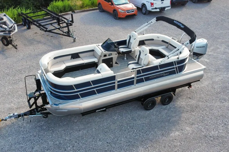 Slide: The Image of 2026 Montego Bay 8522 BR DLX pontoon boat on trailer, parked in gravel lot. - 3