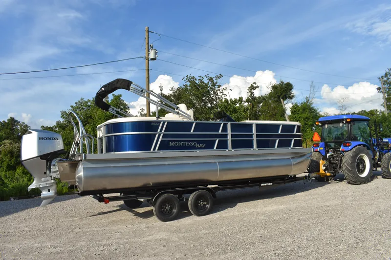 Slide: The Image of 2026 Montego Bay 8522 BR DLX pontoon boat on trailer, hitched to a blue tractor. - 5