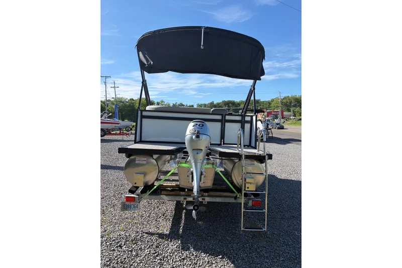 Slide: The Image of 2026 Whisper S17 pontoon boat with canopy and outboard motor, parked on gravel. - 6