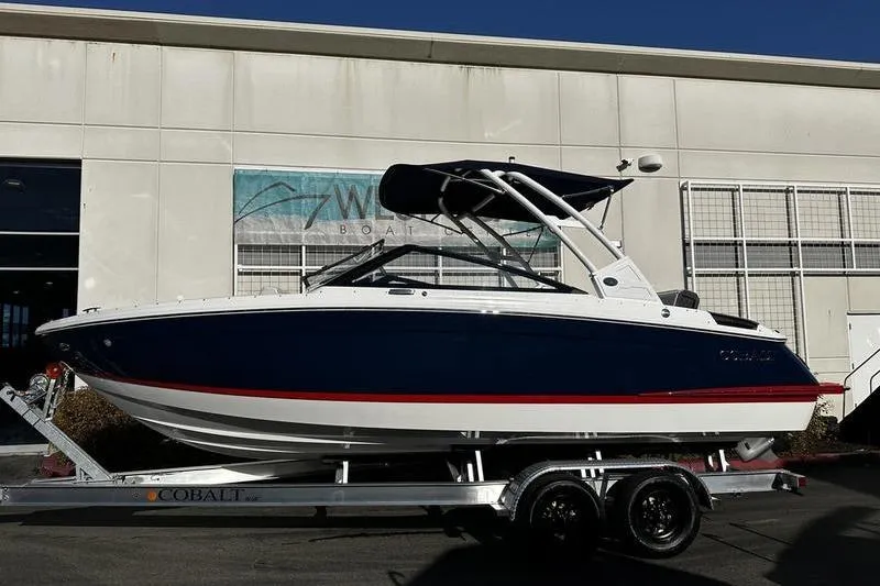 The Image of 2025 Cobalt R4 boat on trailer, blue and white design, parked outside a building. - 0
