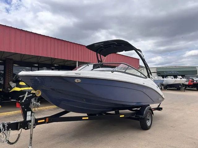 Slide: The Image of 2024 Yamaha Boats 195S on trailer in front of red building. - 8