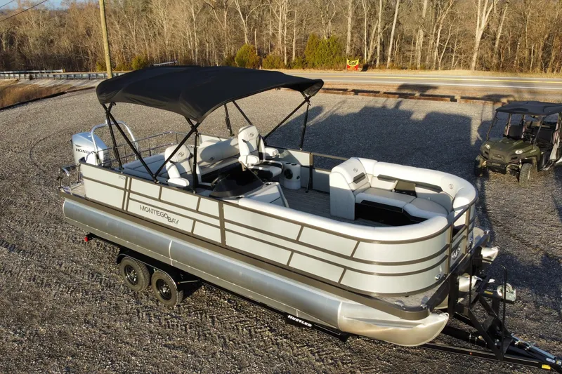 Slide: The Image of 2026 Montego Bay ST8524 SB DLX pontoon boat on trailer, parked outdoors. - 6