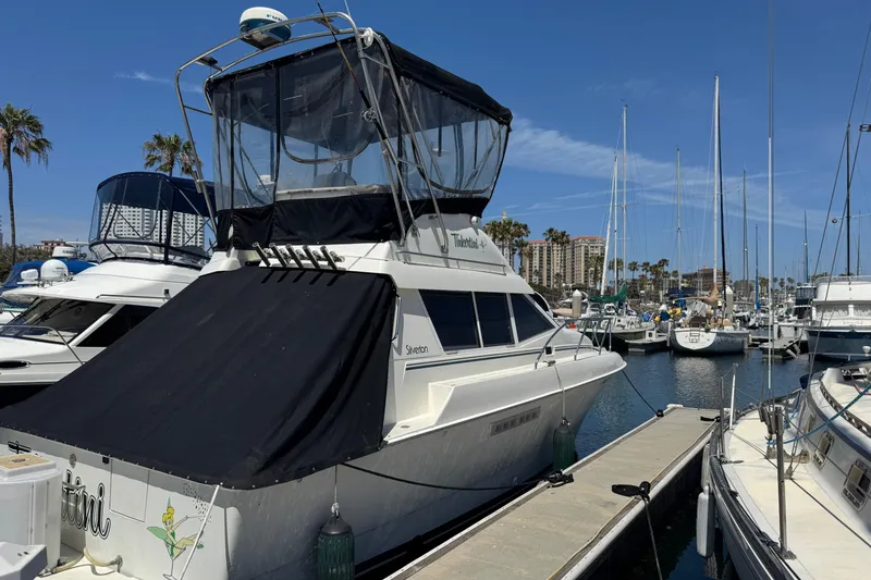 Slide: The Image of 1995 Silverton 31 Convertible yacht docked at a marina under clear blue skies. - 1