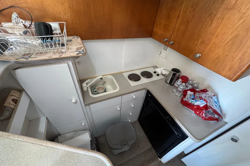 Slide: The Image of Compact kitchen area in a 1995 Silverton 31 Convertible boat, featuring a sink and stove. - 20