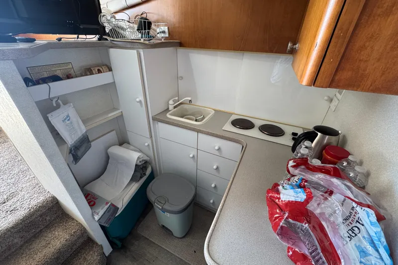Slide: The Image of Compact kitchen area in a 1995 Silverton 31 Convertible boat, featuring a sink and stove. - 21