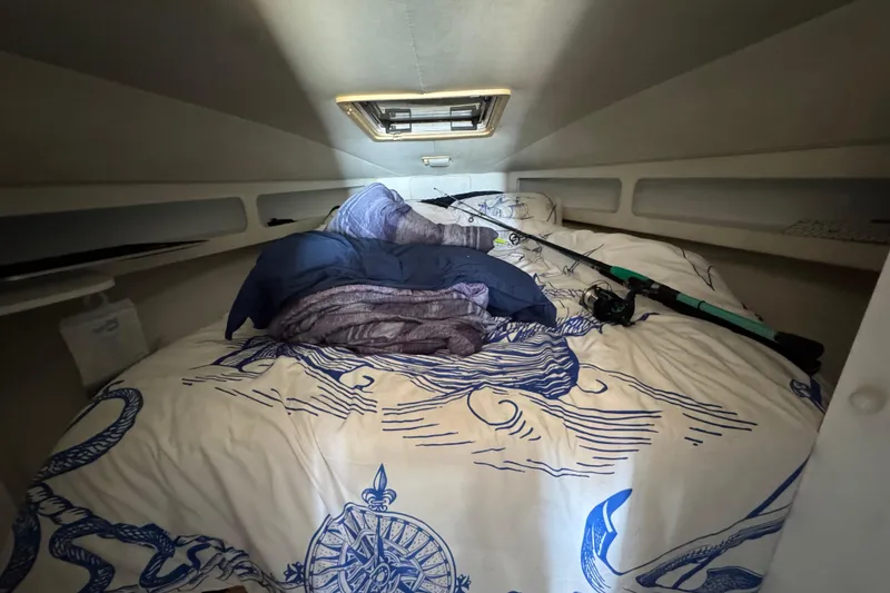 Slide: The Image of Cozy cabin interior of 1995 Silverton 31 Convertible with nautical bedding and fishing rod. - 27