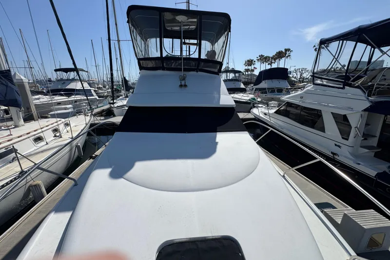 Slide: The Image of 1995 Silverton 31 Convertible yacht docked at marina, surrounded by sailboats. - 7